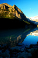 Moon and its reflection on Lake Louise at sunrise
